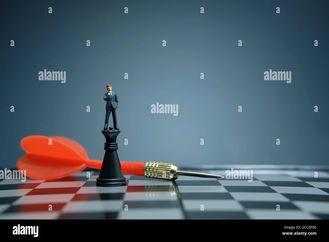 Business-Strategie konzeptuelles Foto - Miniatur Geschäftsmann über Schloss stehen Bauer auf einem Schachbrett mit rotem Pfeil Stockfoto