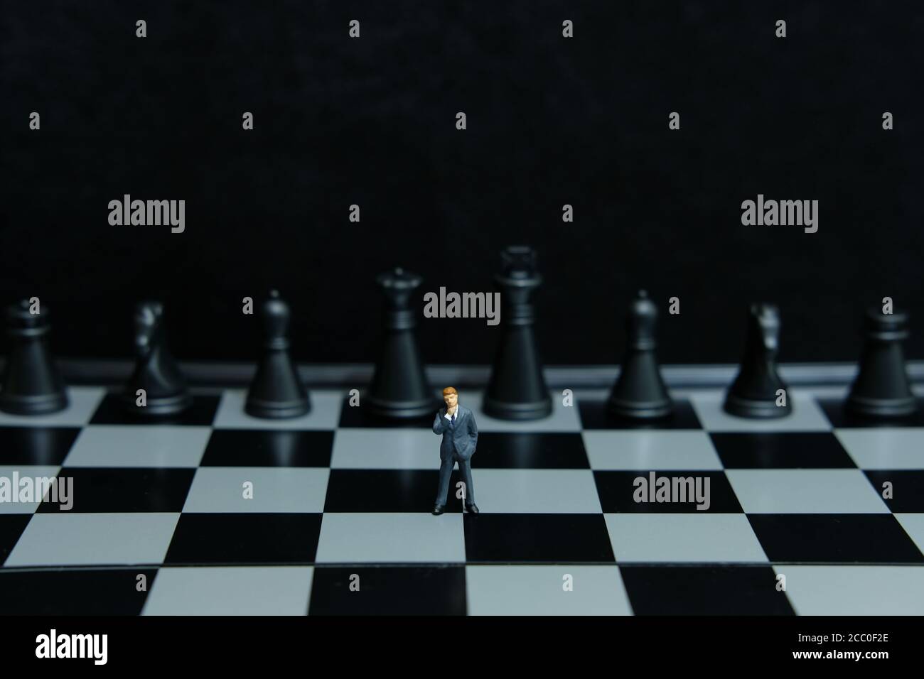 Business-Strategie konzeptionelle Foto - Miniatur des Geschäftsmannes Denken in Vorne schwarzes Schachstück Stockfoto