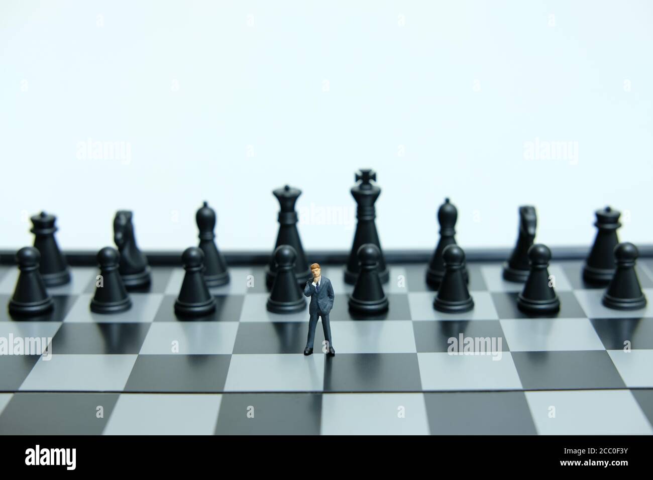 Business-Strategie konzeptionelle Foto - Miniatur des Geschäftsmannes Denken in Vorne schwarzes Schachstück Stockfoto