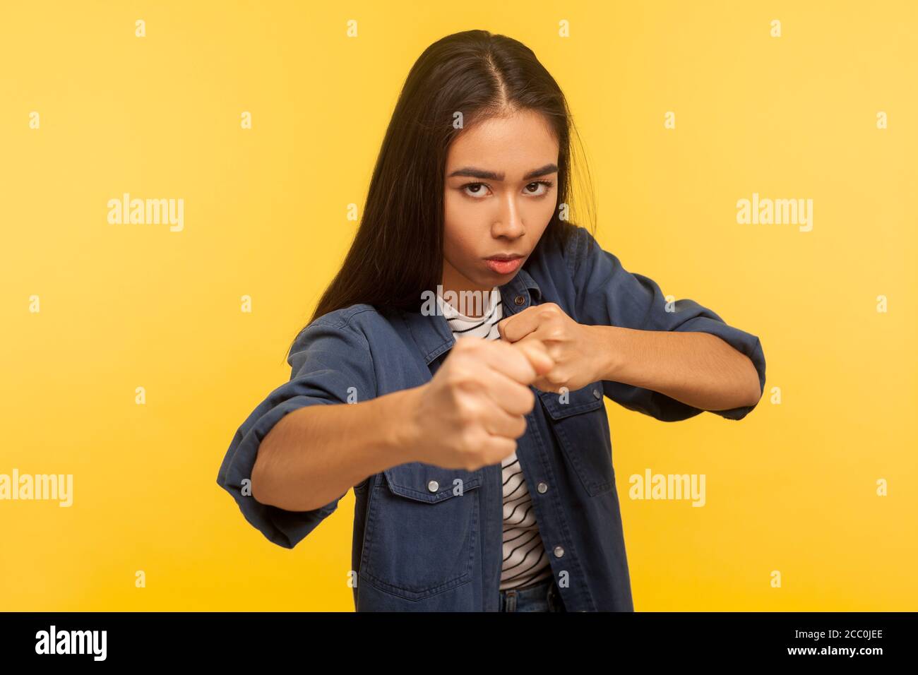 Lasst uns kämpfen! Portrait von selbstbewussten mutigen Mädchen in Denim-Shirt halten Fäuste geballt, Boxen und Stanzen bei der Kamera, ihr Blick Ausdruck Wut Fell Stockfoto