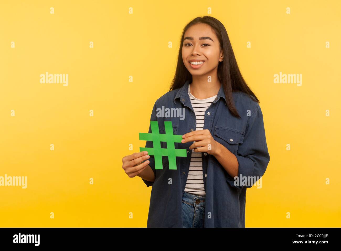 Populäre Internet-Idee, virales Thema. Portrait von glücklichen Mädchen in Denim-Shirt mit Hashtag Symbol und lächeln zur Kamera, Förderung Blog, Web-Trends. In Stockfoto