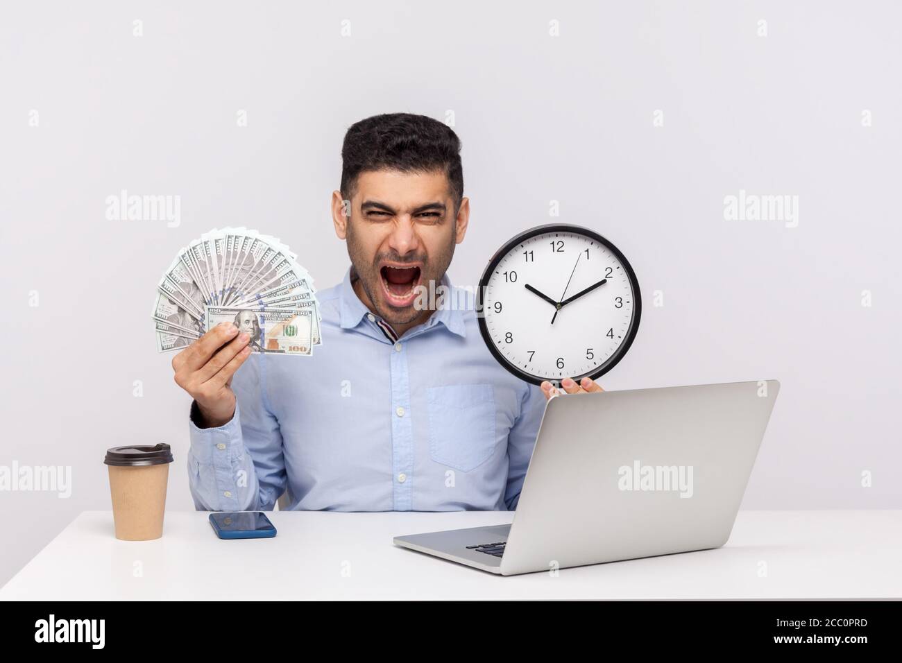 Zeit ist Geld! Aggressiver Geschäftsmann sitzt im Büro Arbeitsplatz, hält große Uhr und Dollar-Banknoten, schreien vor Wut, wütend verrückt. Stockfoto