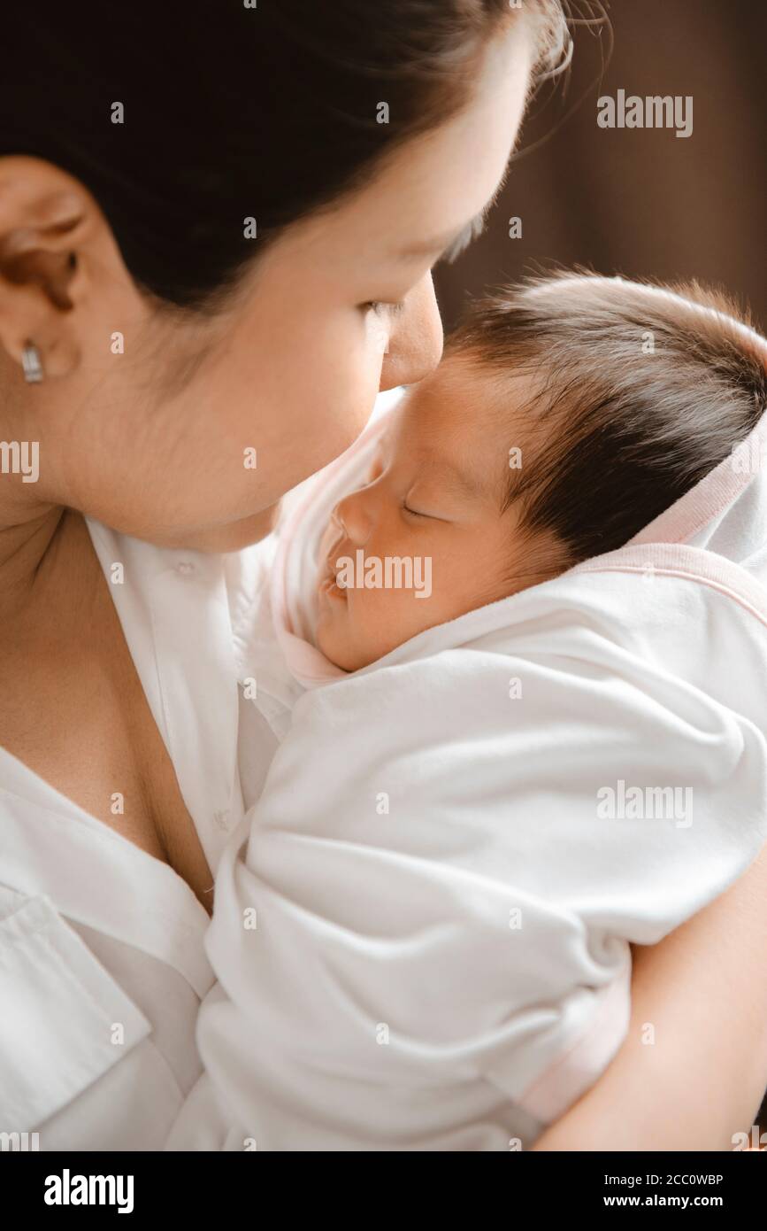 Nahaufnahme einer jungen Frau, die ein neugeborenes Baby in den Armen hält. Stockfoto