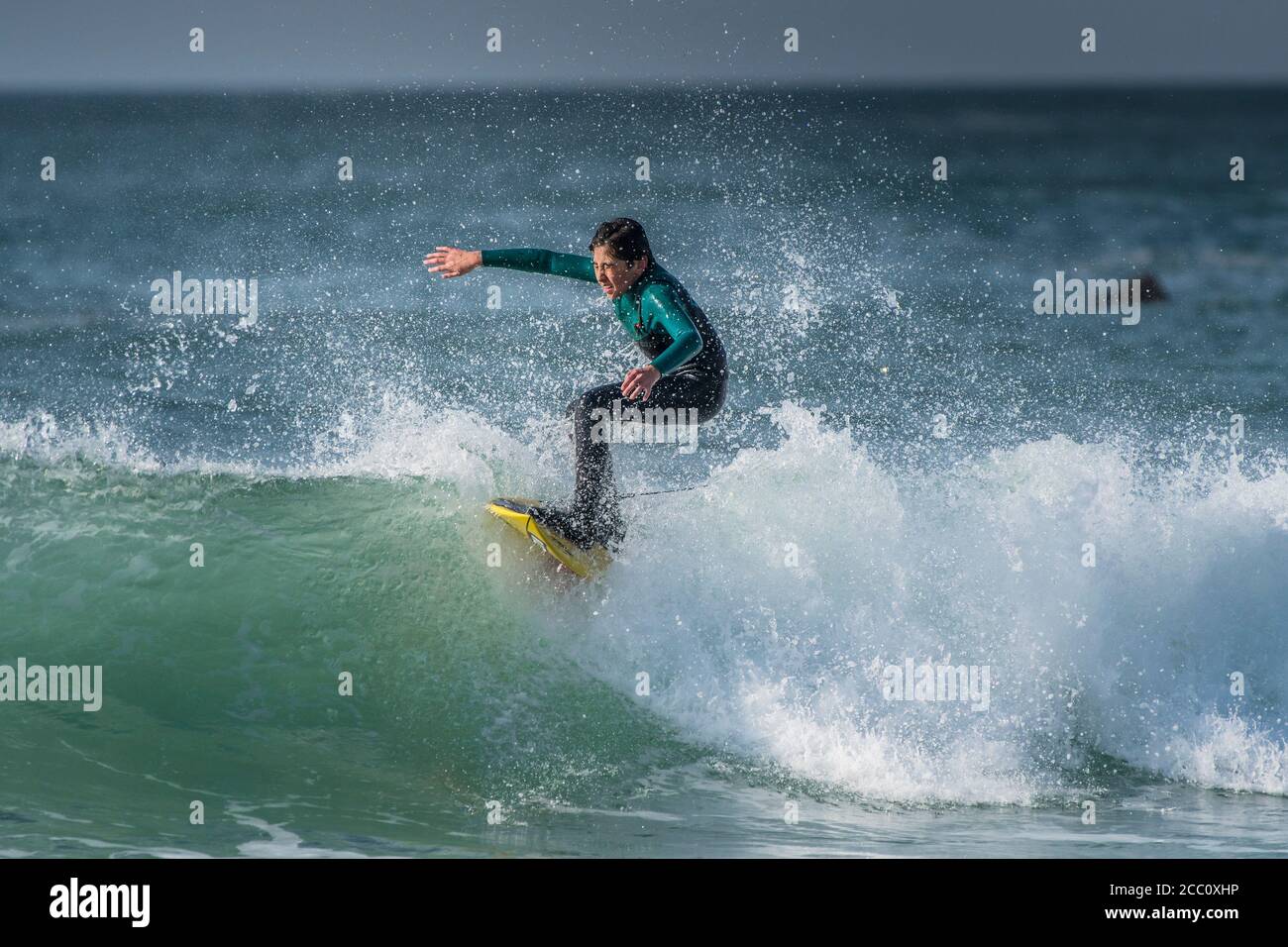 Ein junger Teenager surft auf dem Kamm einer Welle am Fistral in Newquay in Cornwall. Stockfoto