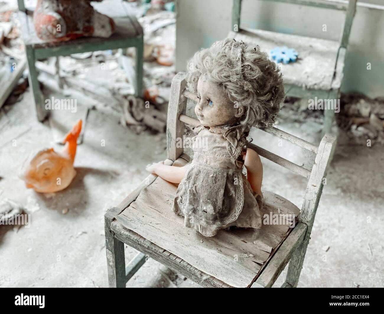 In den Ruinen eines verlassenen Hauses ist Kinderspielzeug mit Staub und Trümmern bedeckt. Verlassene und zerstörte Häuser nach dem Unfall in Tschernobyl nu Stockfoto