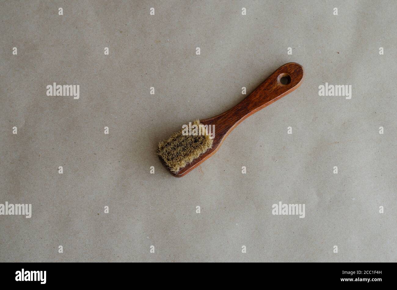 Alte kleine Kleiderbürste auf braunem Papier. Handwerkzeug zum Reinigen von Kleidung. Kleiderbürste aus Holz. Selektiver Fokus. Stockfoto