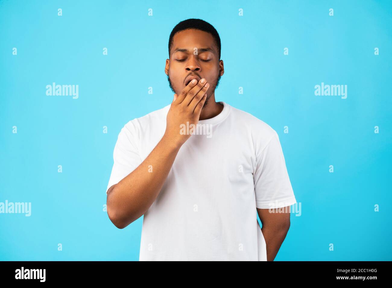 Schläfrig Gelangweilt African Guy Gähnen Mit Geschlossenen Augen, Blauer Hintergrund Stockfoto