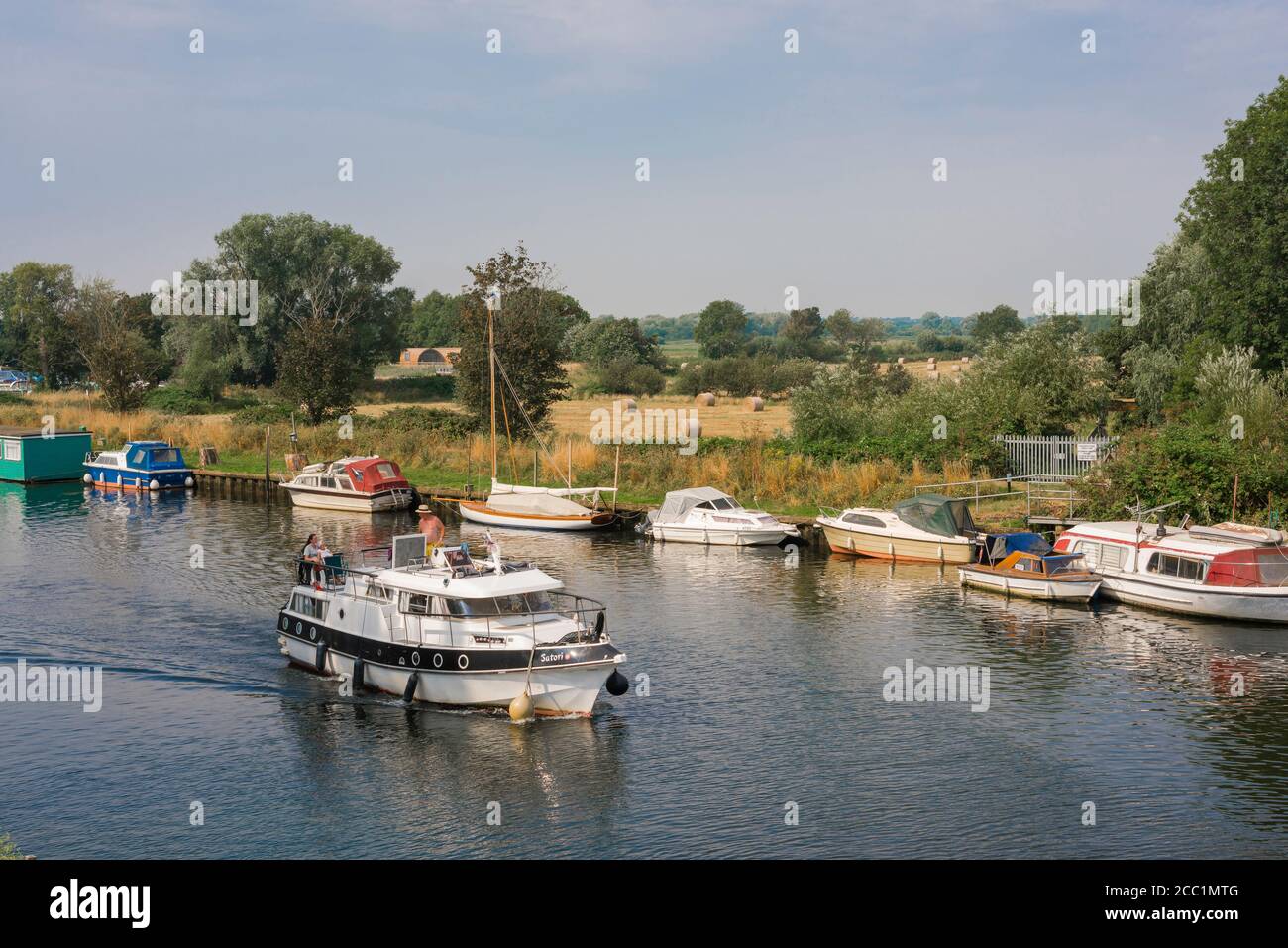 Waveney Valley, Blick auf ein Vergnügungsboot, das den Fluss Waveney mit Booten entlang der Norfolk-Seite des Flusses, East Anglia, England, Großbritannien, fährt Stockfoto