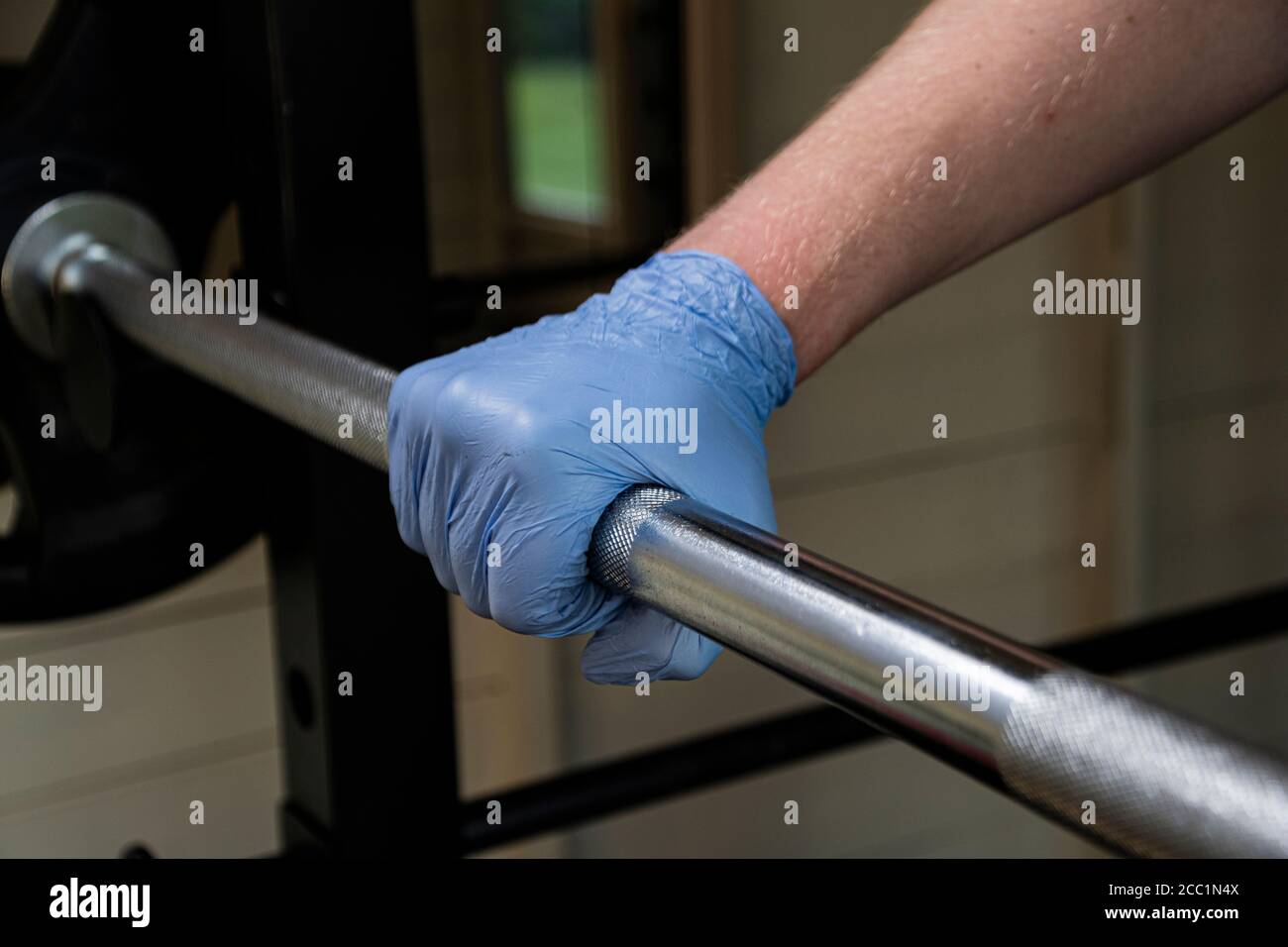 Gummihandschuhe, die in einer Turnhalle getragen werden, um Gewichte zu heben und Krankheiten wie Coronavirus zu vermeiden, könnte die Metallhantel Spuren von covid-19 haben Stockfoto