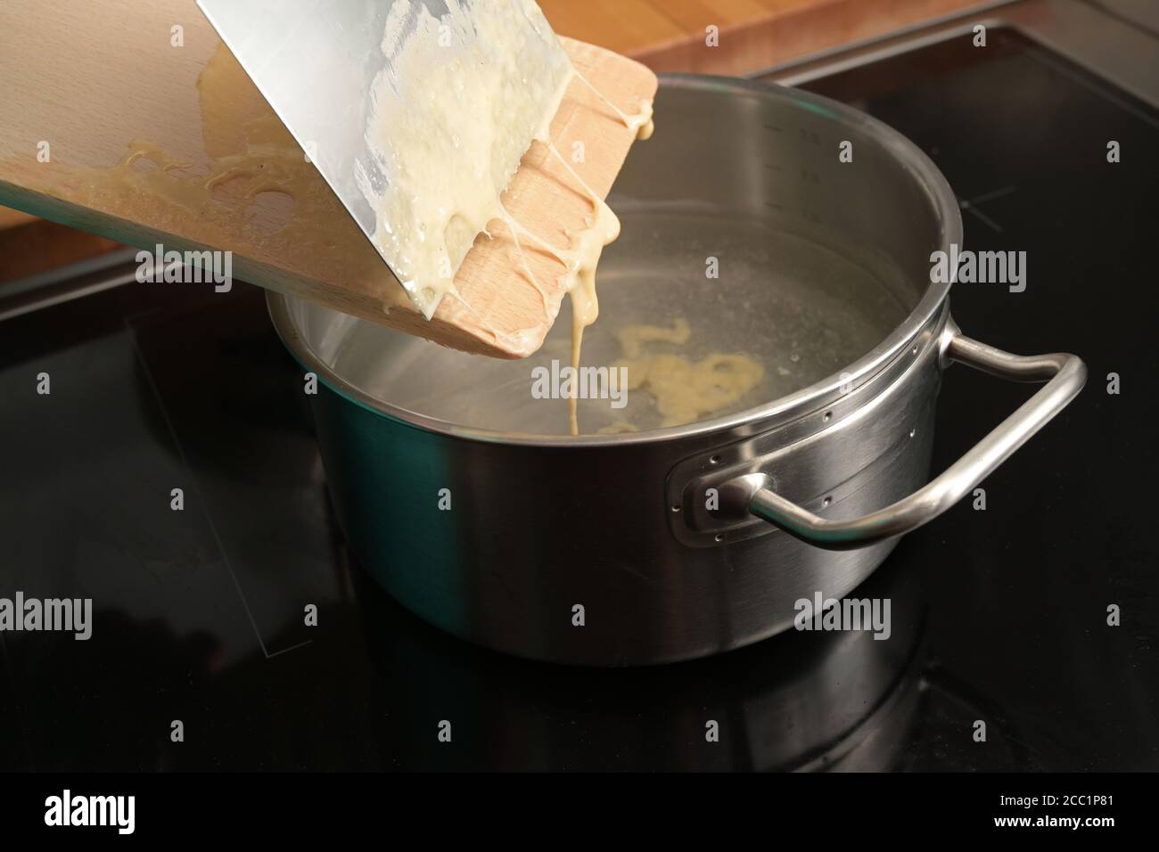 Kochen spätzle, hausgemachter Eiernudelteig wird von einem Holzbrett in kochendes Wasser geschabt, typisches Gericht in Schwaben, Süddeutschland und Österreich, Stockfoto
