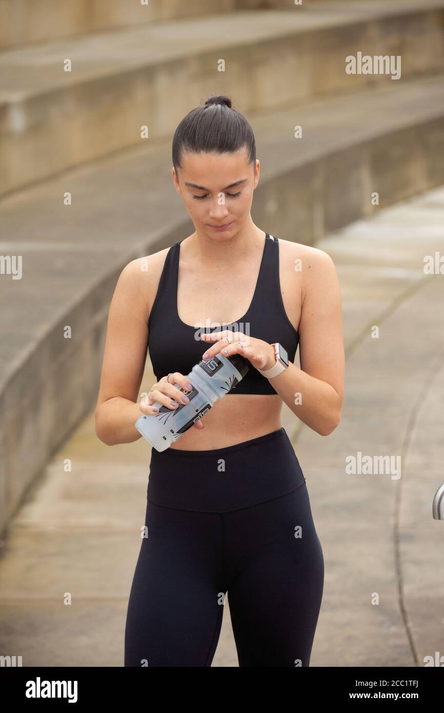 Porträt einer athletischen jungen Frau, die eine Trinkflasche hält Leggings und Sport-BH Stockfoto