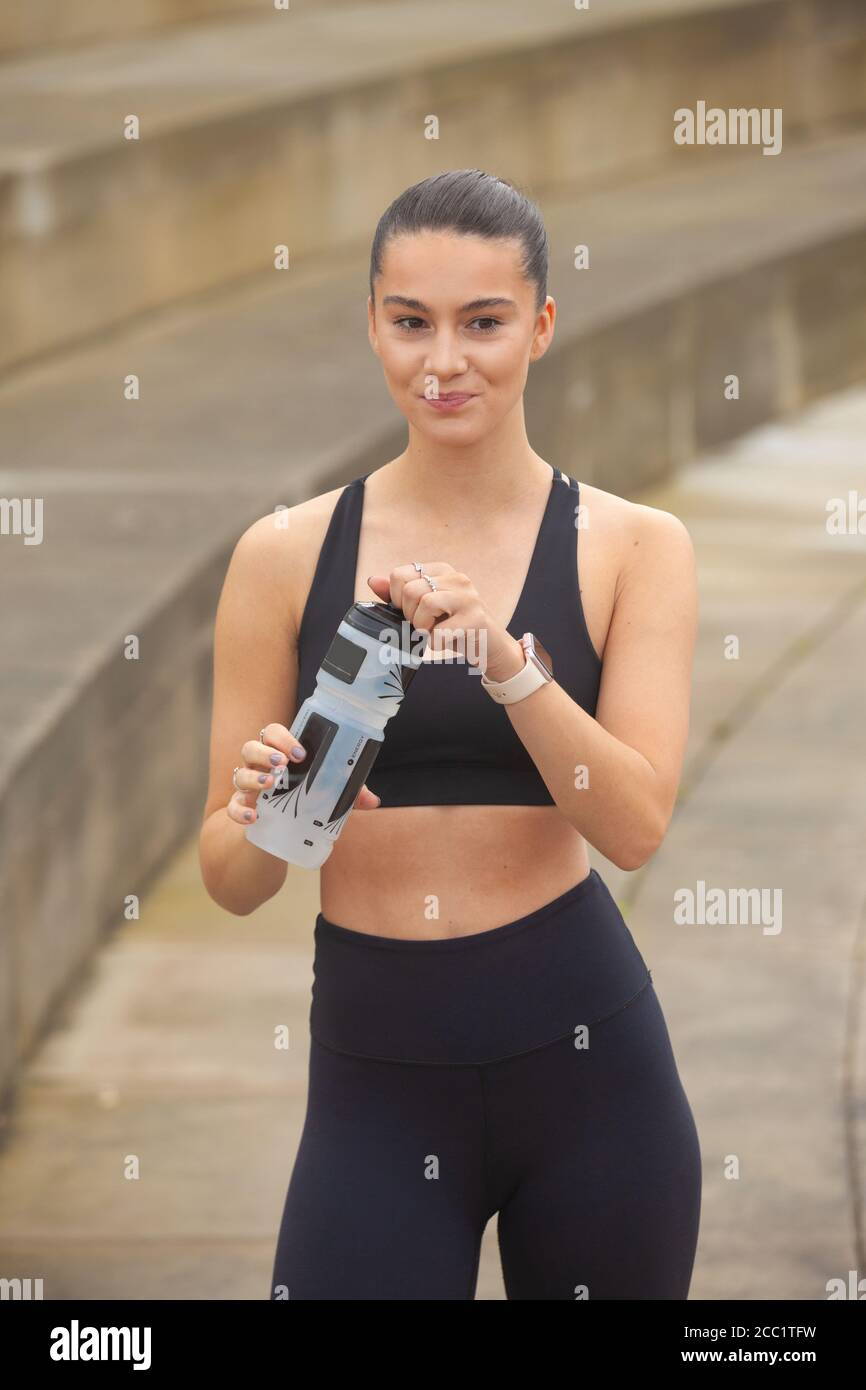 Porträt einer athletischen jungen Frau, die eine Trinkflasche hält Leggings und Sport-BH Stockfoto
