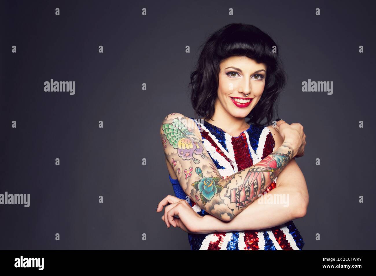 Junge Frau mit Tattoo auf der Hand vor grauem Hintergrund Stockfoto