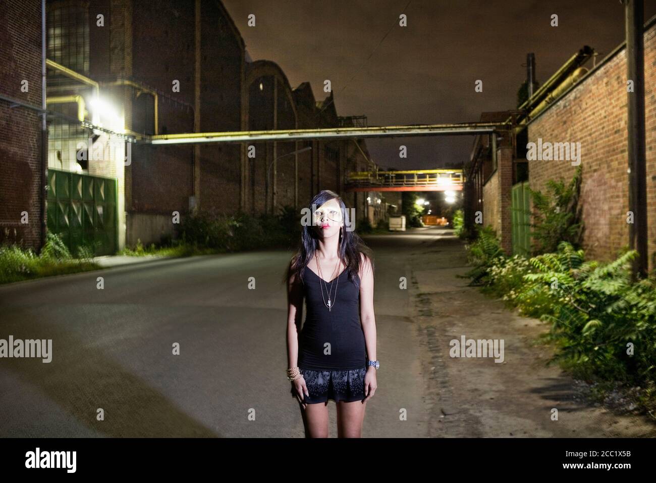 Deutschland, Köln, junge Frau, die auf leere Straße, Porträt Stockfoto