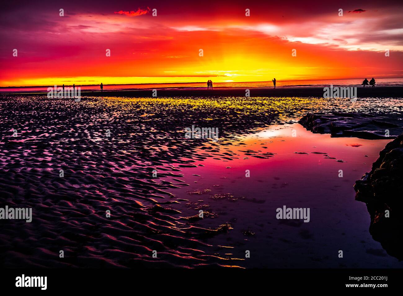 Die Menschen stehen sehr früh auf, um den leuchtend roten Himmel vom Hurrikan weit vor der Küste zu sehen. Aber keine Sorge, jeder ist vor diesem Hurrikan vor der Küste sicher. Stockfoto