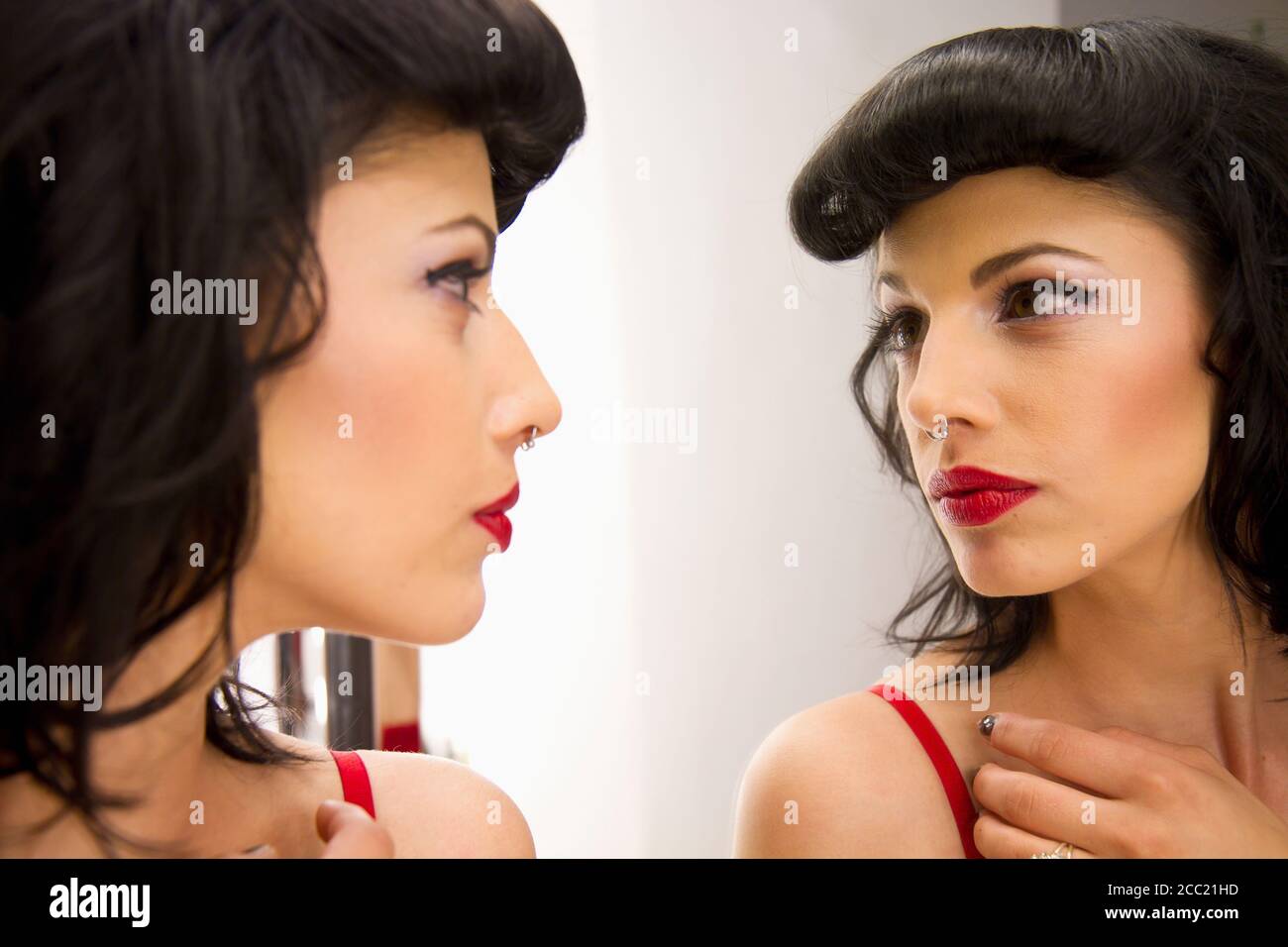 Junge Frau mit Nase piercing Blick in Spiegel Stockfoto