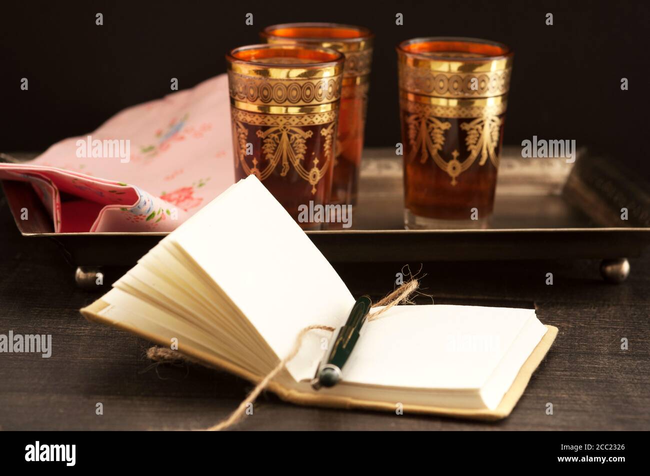 Schwarzer Tee mit Buch auf Holztisch, Nahaufnahme Stockfoto