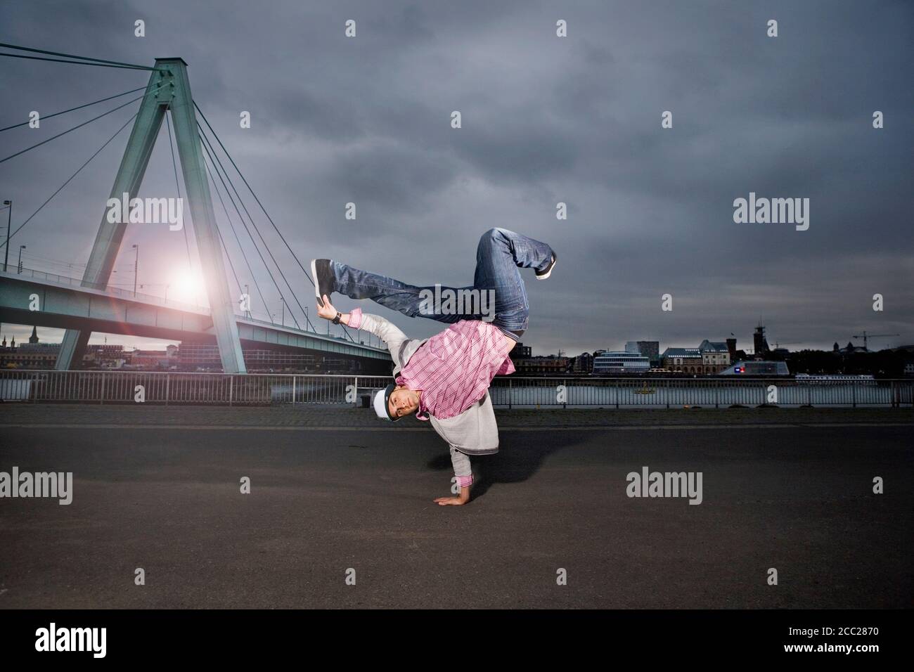 Deutschland, Köln, junger Mann darstellende Breakdance, Rheinbrücke im Hintergrund Stockfoto