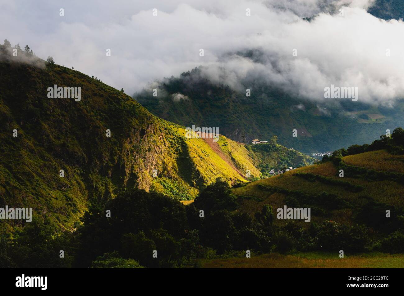 Der hohe Himalaya unter dem Teppich der Wolken verschlungen das kleine ländliche Dorf in der Ferne bei den Morgenstunden im Sommer nahe Tawang, Arunachal Pradesh, Indien. Stockfoto