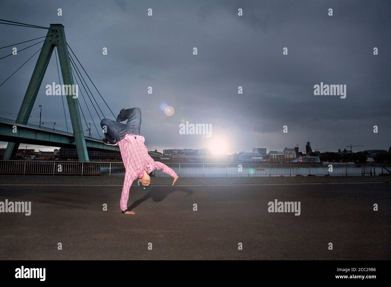 Deutschland, Köln, junger Mann darstellende Breakdance, Rheinbrücke im Hintergrund Stockfoto