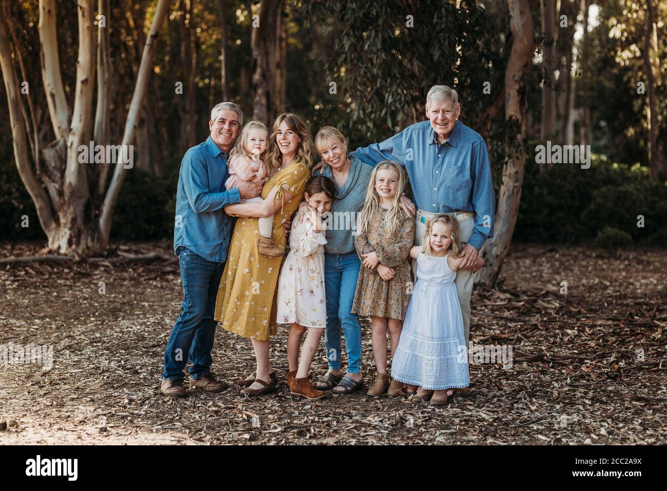 Porträt einer großen lächelnden erweiterten Familie, die draußen im Wald umarmt Stockfoto