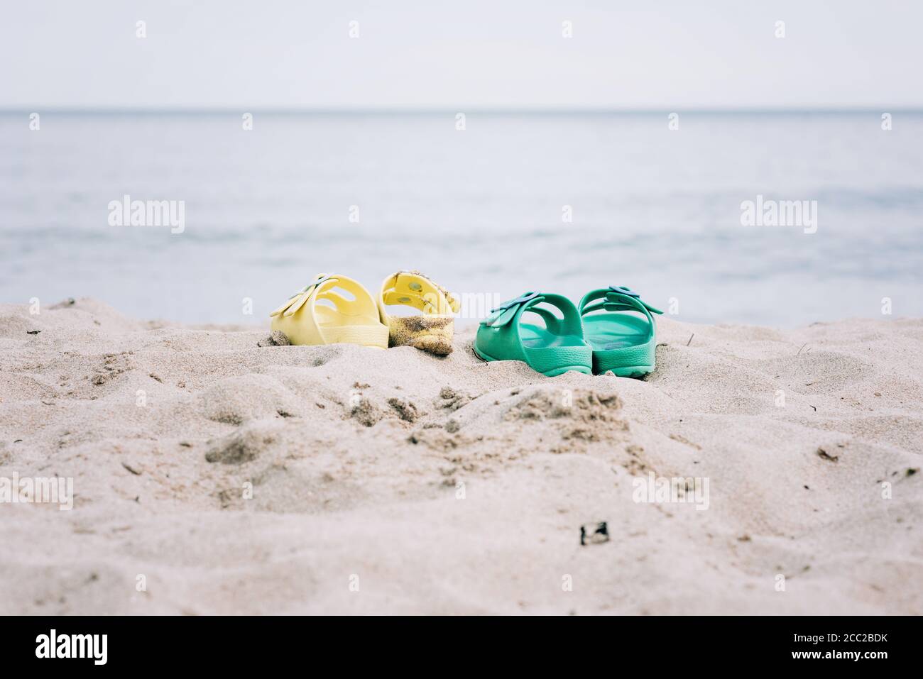 Zwei Paar Sandalen an einem Sandstrand im Sommer Stockfoto