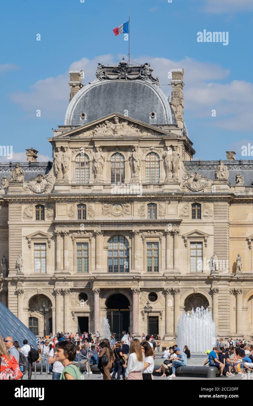 Louvre Museum Paris mit Besuchern an hellen sonnigen Tag. Menschen stehen in der Schlange oder entspannen. Stockfoto