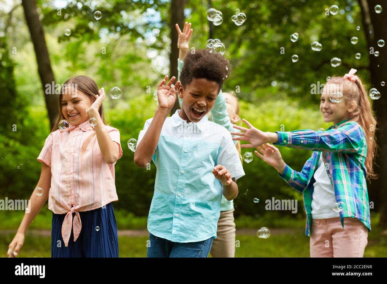 Waist up Porträt der multi-ethnischen Gruppe von unbeschwerten Kindern spielen Mit Blasen im Freien im Park Stockfoto