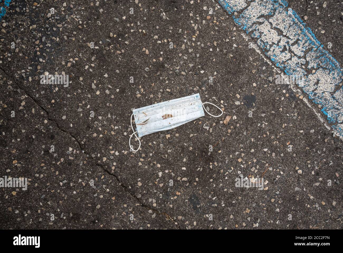 Weggeworfene Gesichtsmaske, verwendet und auf einem Restaurantparkplatz während der Covid-19 Coronavirus-Pandemie von 2020 weggeworfen. Stockfoto