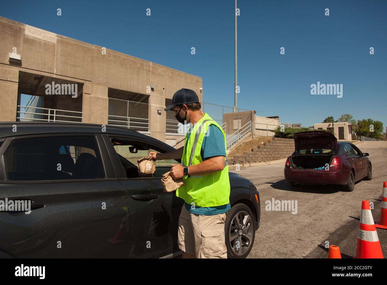 Cedar Rapids, Iowa, USA. August 2020. 15. Aug. 2020: Hunderte von Autos stehen an, um kostenloses Wasser, Eis und Schelfgerichte abzuholen. Die Nationalgarde kam am Donnerstag, 3 Tage nach dem Sturm, an und begann am nächsten Tag, einige Vorräte zu übergeben. Der Großteil der Hilfe kommt jedoch von gewöhnlichen Menschen, die sich gegenseitig helfen. Cedar Rapids und viele der umliegenden Grafschaften wurden am 10. August von einem Derecho getroffen. Fast eine Woche später, und viele Menschen sind immer noch ohne Strom, einige schlafen in Zelten und Plätze ohne Klimaanlage und Warmwasser, in der Hoffnung, die Nation wird darauf achten, wha Stockfoto