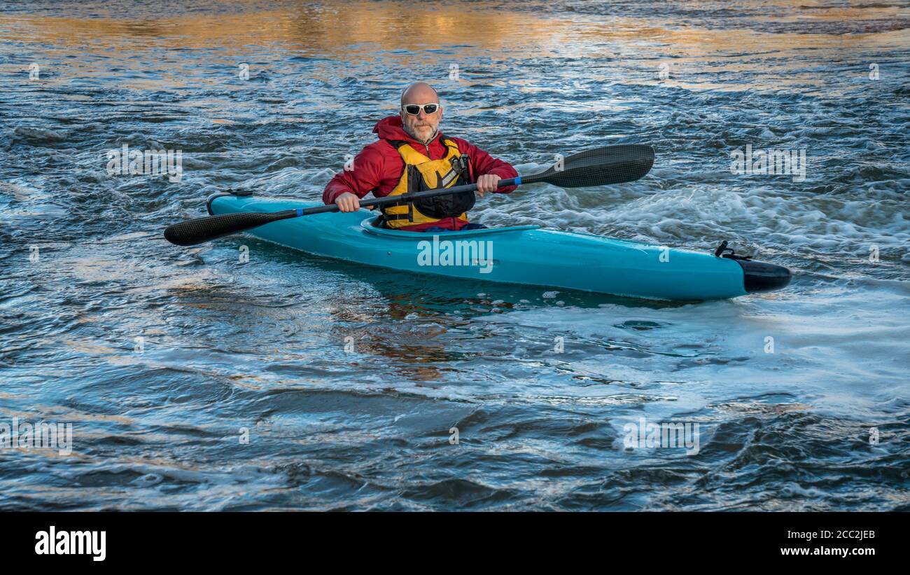 Ältere Männer paddeln ein Wildwasser-Kajak auf einem turbulenten Fluss - South Platte River im Norden von Colorado, Fitness-und Erholungskonzept Stockfoto