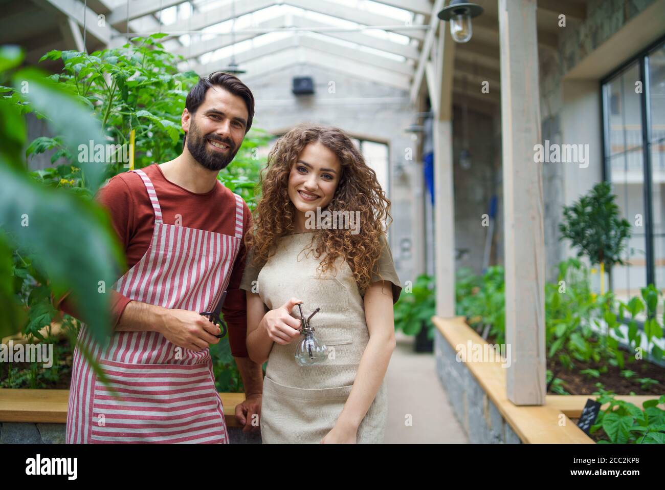 Porträt eines Gärtners, der im Gewächshaus steht und die Kamera anschaut. Stockfoto