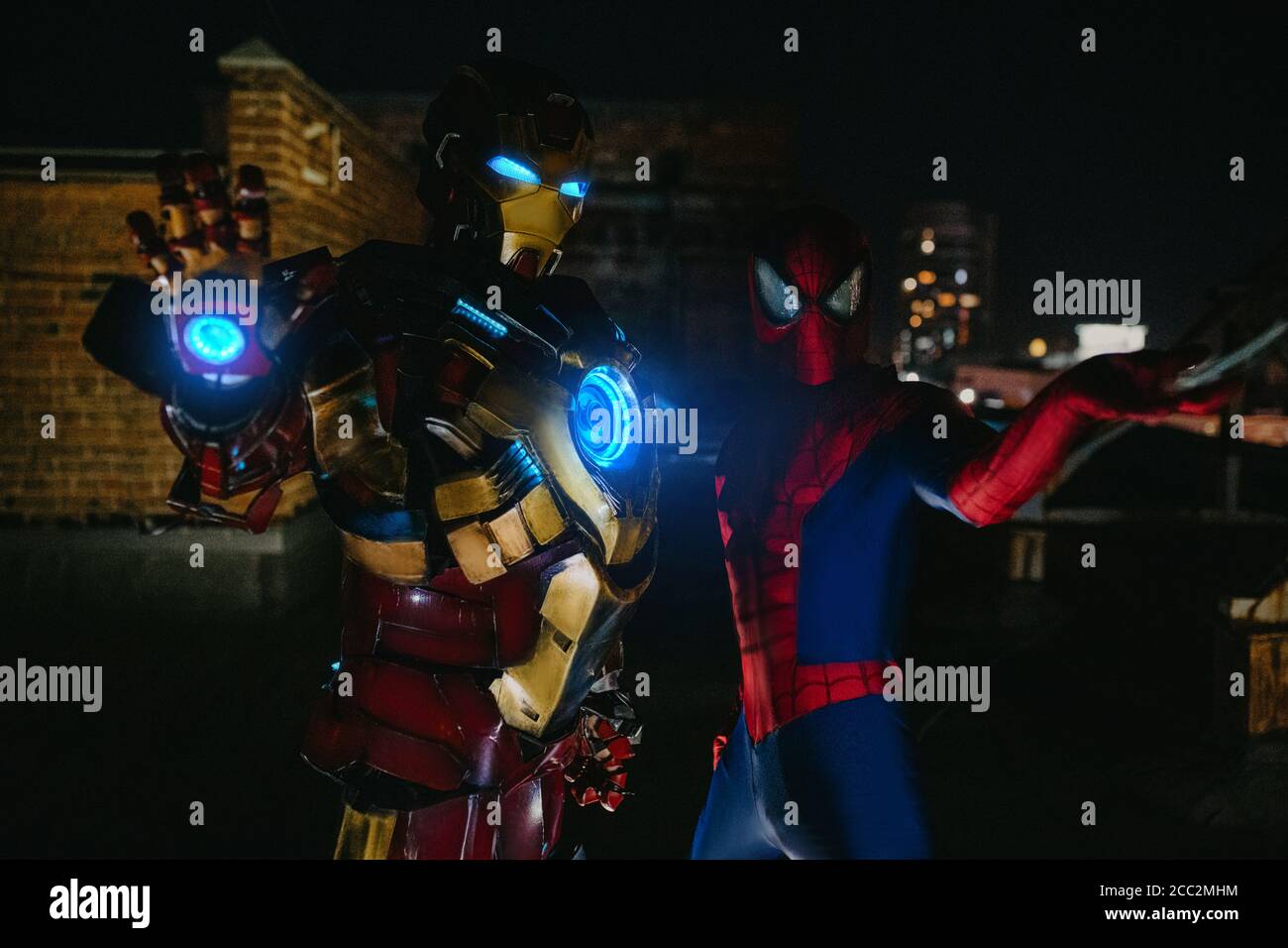 Zwei Cosplayer stehen zusammen in Bildern einer Figur Spider-man und Iron man gegen Stadtbild und Nachtlicht. Stockfoto