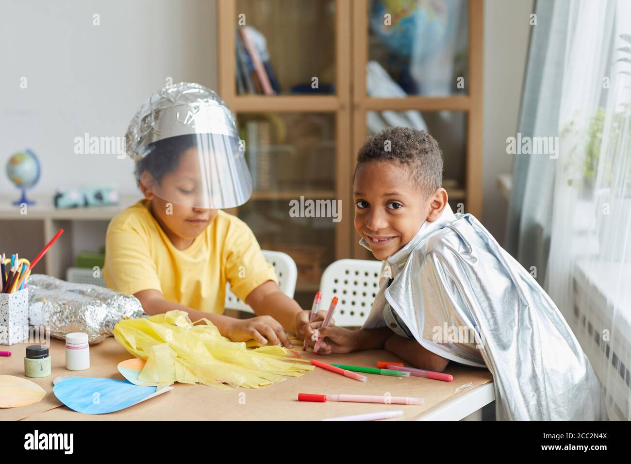 Portrait von zwei afroamerikanischen Jungen, die Raum Anzüge machen, während sie Kunst und Handwerk Unterricht im Kindergarten oder Entwicklungszentrum genießen, Raum kopieren Stockfoto