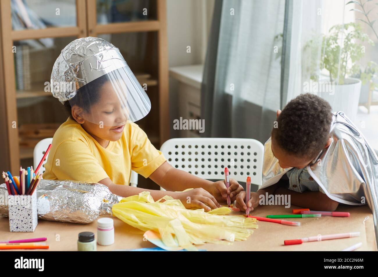 Portrait von zwei afroamerikanischen Jungen, die Astronauten spielen und Raum machen Anzüge während genießen Kunst und Handwerk Unterricht in der Vorschule oder Entwicklungszentrum Stockfoto