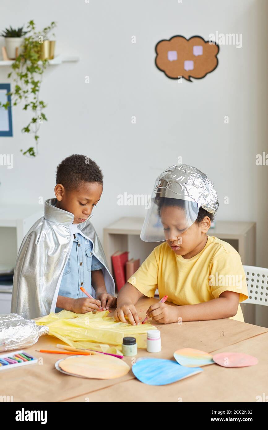 Vertikales Porträt von zwei afroamerikanischen Jungen, die Astronauten spielen und machen Raum Anzüge während genießen Kunst und Handwerk Unterricht in der Vorschule Oder Entwicklung Stockfoto