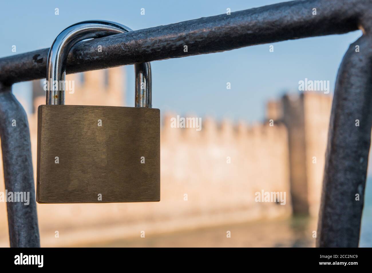 Leeres Vorhängeschloss auf der Brücke in Sirmione, Gardasee, Italien. Die Burg von Rocca Scaligera im Hintergrund. Stockfoto