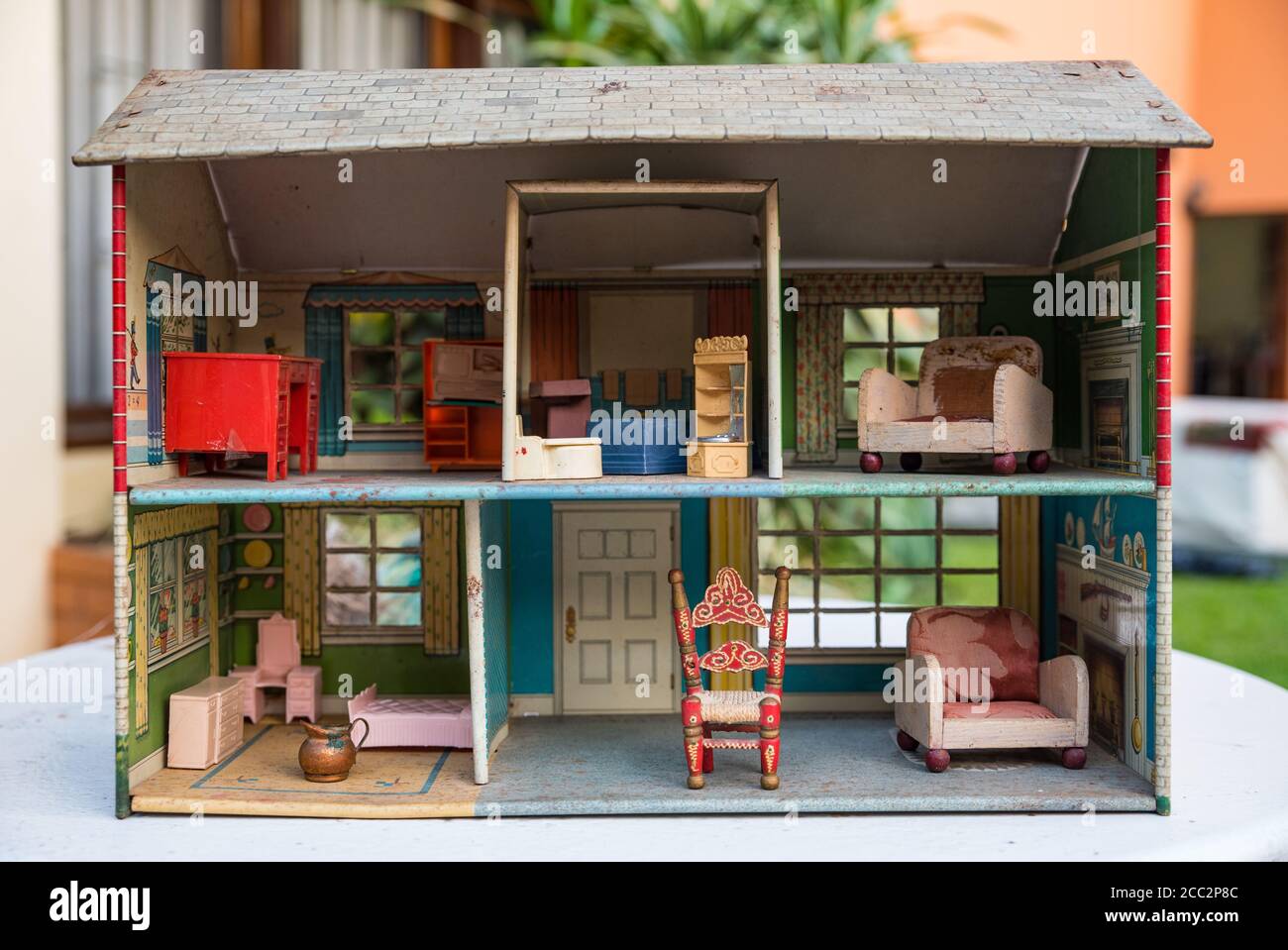 Vintage Metall Puppenhaus mit Möbeln auf einem Tisch im Garten. Stockfoto