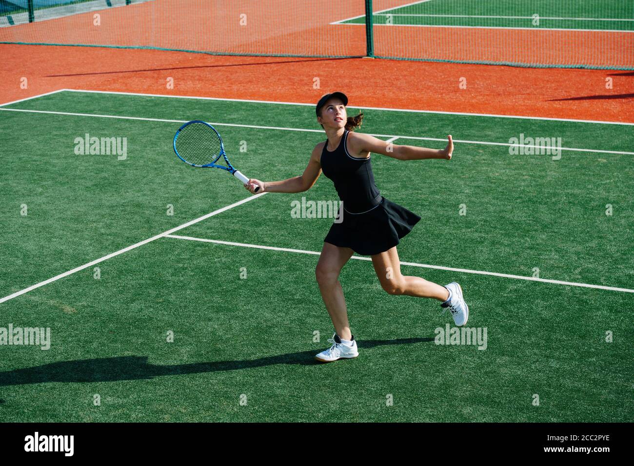 Running Teenager Mädchen bereit, Overhead-Tennisball zurück Stockfoto