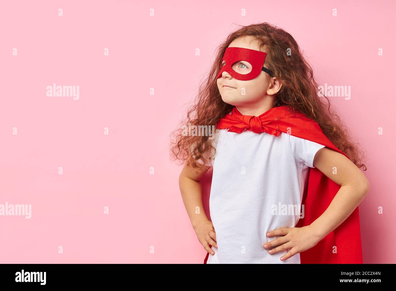Die Fantasie des Superhelden. Kaukasischen Kind trägt rote Maske des Helden  und Mantel stehen suchen Seite, lockiges kleines Mädchen drwam zu  Superhelden sein Stockfotografie - Alamy