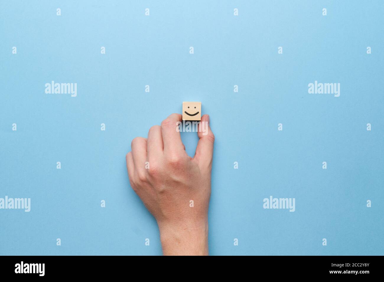 Gute Stimmung Smiley Konzept auf einem Holzwürfel mit einem Hand Stockfoto