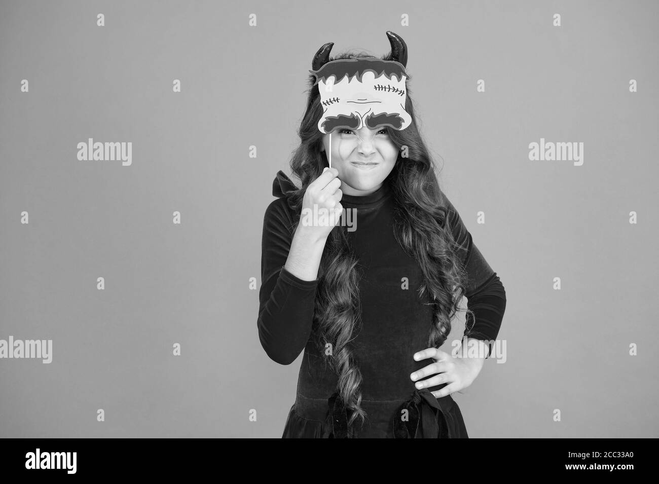 Freakishly Scary Halloween. Scary Halloween Kind orange hinterlegt. Party Girl mit furchterregend aussehen. Fashion kid tragen rote Teufel Hörner und Requisiten. Beängstigend Urlaubszeit. Stockfoto