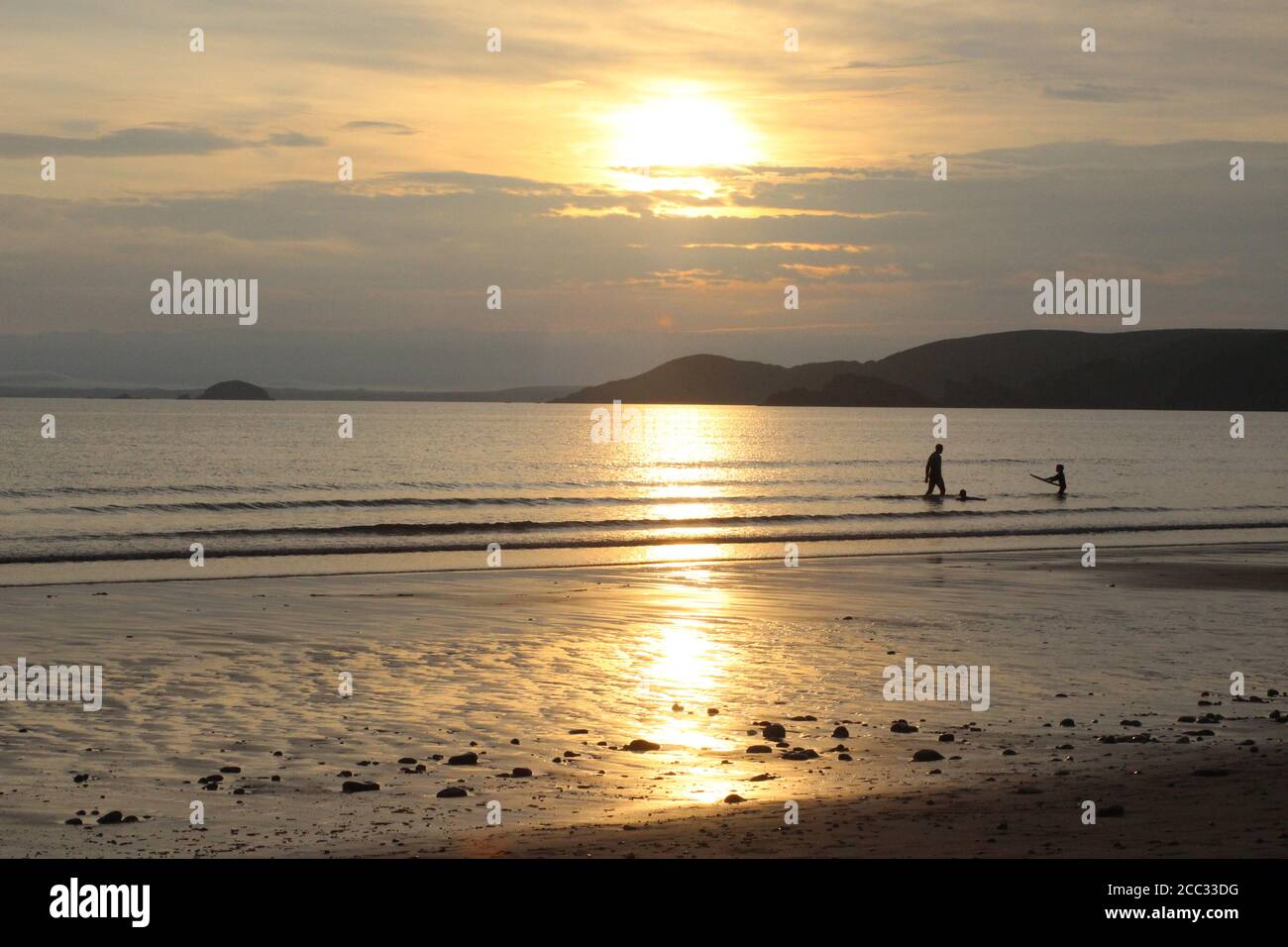 Menschen, die bei Sonnenuntergang im Meer spielen, Newgale, Pembrokeshire, Wales, Großbritannien, August 2020 Stockfoto