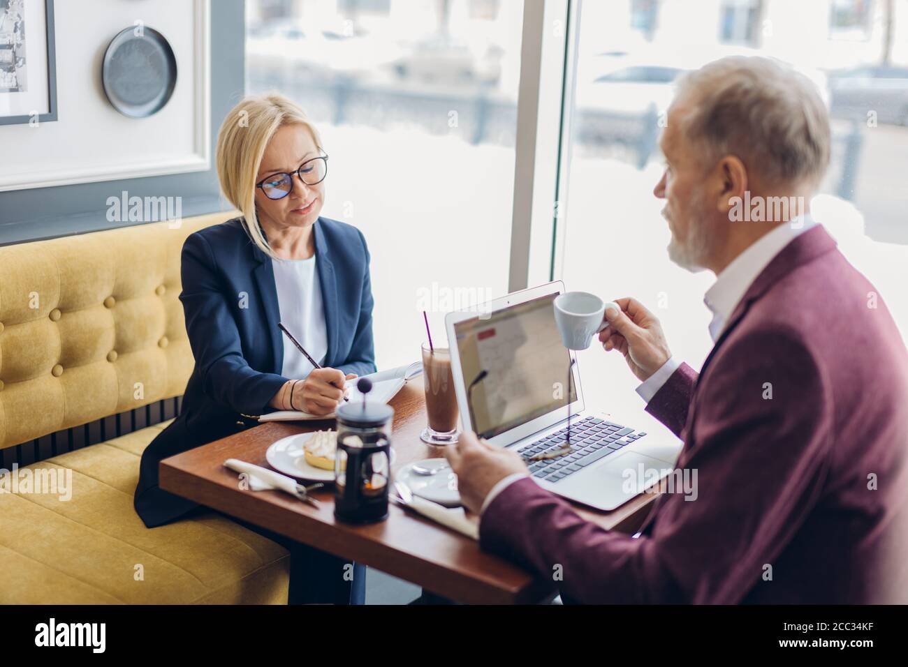 Ehrfürchtige Frau in stilvoller Kleidung und alten Mann mit einem Geschäftsmeeting.formelles Gespräch in informellem Stil Stockfoto