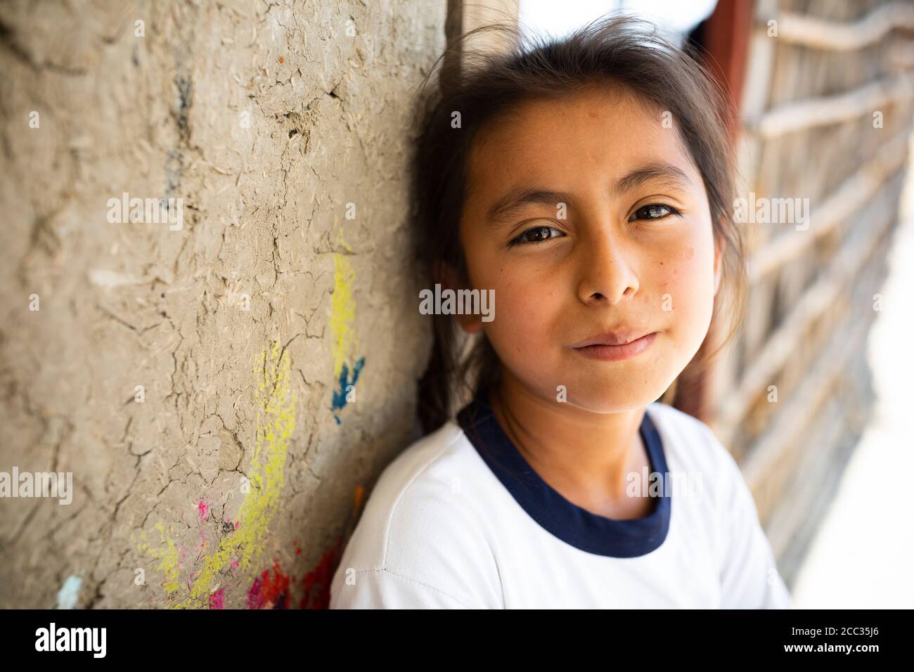 Ein zehnjähriges Mädchen steht in der Tür des Lehmhauses ihrer Familie in der ländlichen Provinz Sullana, Peru, Südamerika. Stockfoto