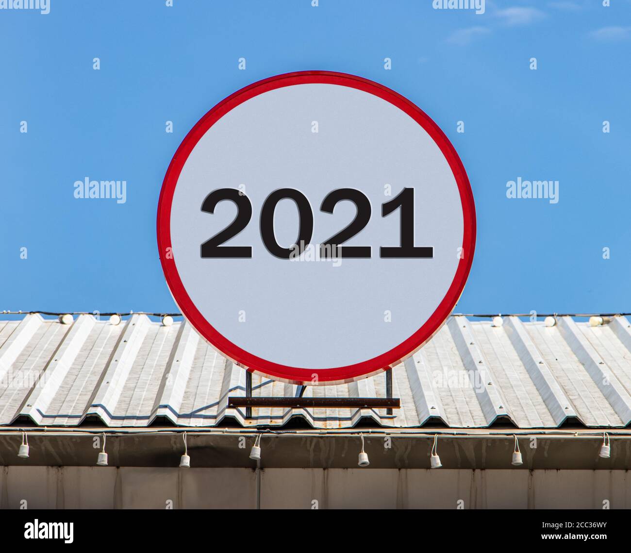 Eine Circle Plakatwand mit der Nummer 2021 ist auf einem Dach installiert. Gruß für das neue Jahr 2021. Stockfoto