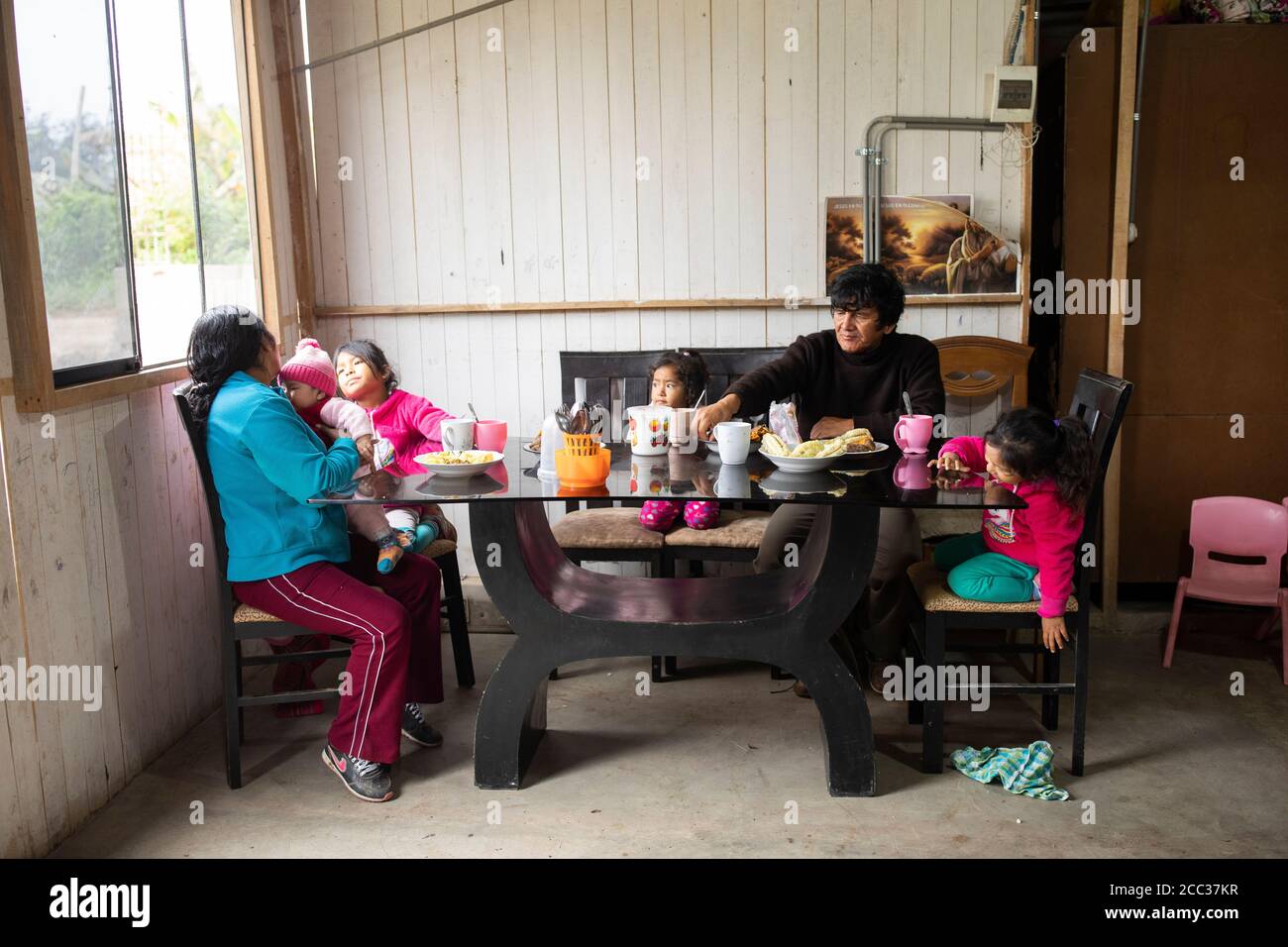 Eine Familie sitzt für ein Frühstück mit Mais und Süßkartoffeln zusammen am Tisch in Manchay Alto, Pachamac District, Peru. Stockfoto