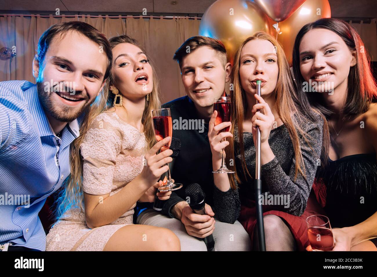 Urlaub in modernen Karaoke, junge Menschen genießen Zeitvertreib in Karaoke zusammen, singen im Mikrofon und rauchen Shisha, rauchen in isolierten Raum Stockfoto