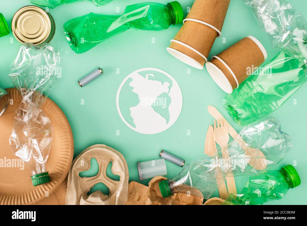 Draufsicht auf Plastikflaschen, Akkumulatoren und Einweg-Geschirr in der Nähe von Papier Erde Zeichen auf grünem Hintergrund, Ökologie Konzept Stockfoto