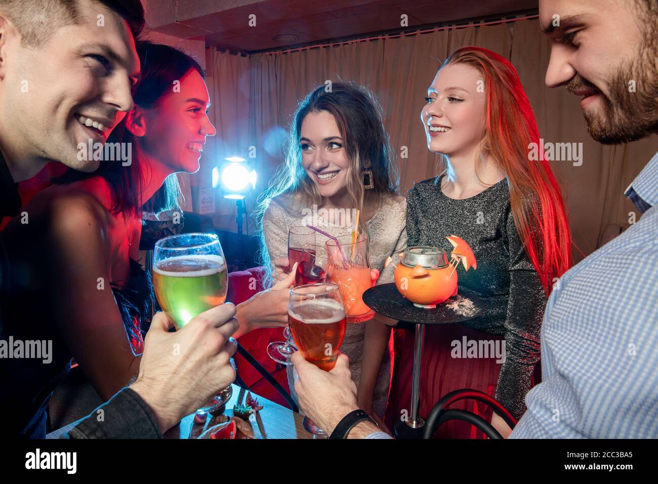 kaukasische Gruppe von Freunden trinken und haben Spaß zusammen in Karaoke-Bar, schöne Mädchen und gutaussehende Jungs chillen und rocken zusammen, haben Freizeit Stockfoto